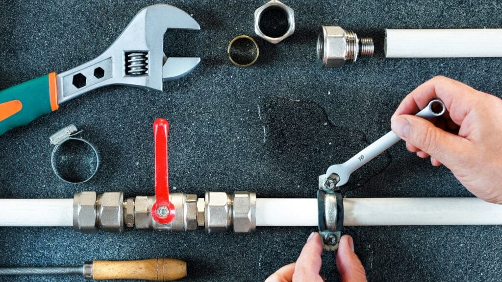 Plumber repairing a pipe valve with an adjustable wrench in Suwanee