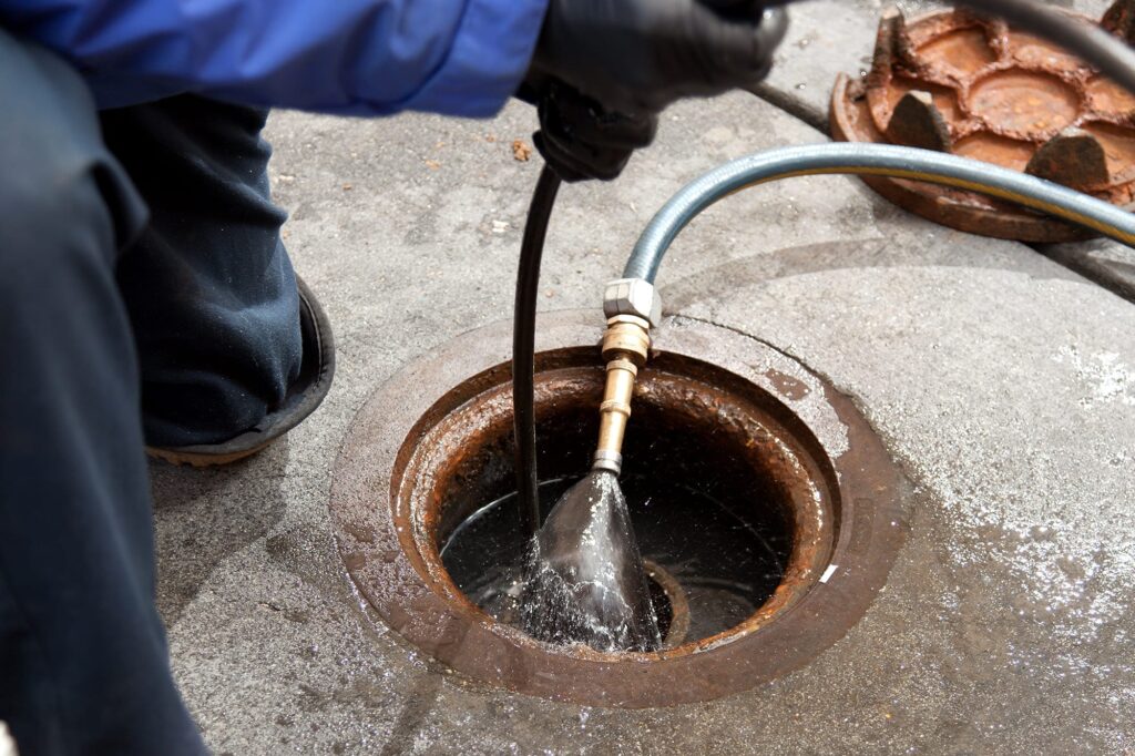 Plumber hydro jetting a sewer line through a manhole in Suwanee