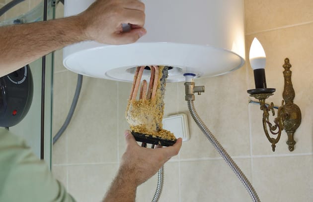 Technician removing mineral buildup from a water heater in Suwanee